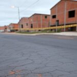 Rua em Ceilândia com marcas de arrasto no asfalto e fita policial, representando cena de agressão e fuga de agressor.