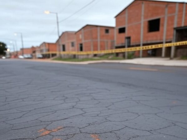 Rua em Ceilândia com marcas de arrasto no asfalto e fita policial, representando cena de agressão e fuga de agressor.