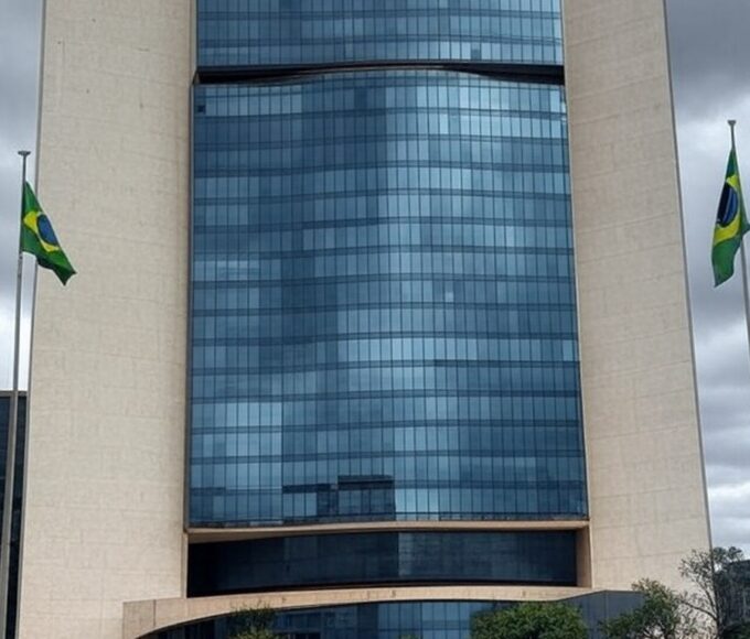 Edifício do Tribunal de Justiça do DF em Brasília com bandeiras a meio mastro, representando luto pela morte de desembargador.