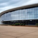 Escritório governamental vazio em Brasília com calendários de folgas de aniversário e pilhas de documentos, representando sobrecarga orçamentária e ameaça à produtividade.