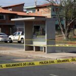 Parada de ônibus em Planaltina com fita de isolamento e viatura da Polícia Civil do DF, em cena de investigação.