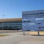 Sala de sessões vazia na CLDF em Brasília, com documentos desorganizados e telas de transmissão, destacando ineficiência e lentidão.