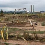 Horta urbana abandonada em Brasília, com plantas secas e estruturas danificadas, ilustrando falhas crônicas na agricultura urbana.