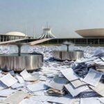 Bebedouro em evento ao ar livre em Brasília, com documentos burocráticos representando sobrecarga para organizadores.