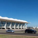 Vista externa do Aeroporto de Brasília, com terminal e aviões, representando anúncio de leilão pelo governo federal.