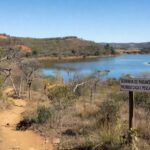 Paisagem da Serrinha do Paranoá transformada em parque ambiental, com vegetação de cerrado e Lago Paranoá ao fundo.