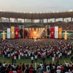 Vista ampla da Arena BRB Mané Garrincha em Brasília durante evento evangélico com símbolos cristãos e iluminação noturna.