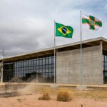 Exterior de tribunal em Planaltina, DF, representando julgamento de chacina no Centro-Oeste, com bandeiras e arquitetura local.