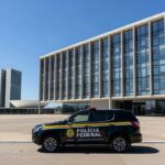 Viatura da Polícia Federal estacionada em frente ao Banco de Brasília, representando operação de prisão.