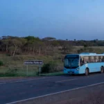 Estrada com placa de divisa do DF e ônibus em movimento pendular na hora azul